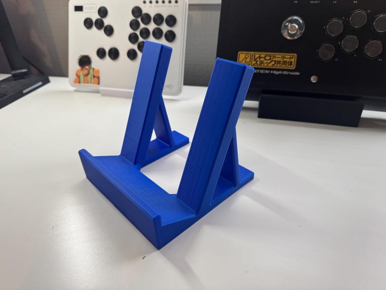 Pu&ograve; includere: Un supporto per telefono in plastica blu con due supporti inclinati. Il supporto &egrave; progettato per tenere un telefono in posizione verticale.