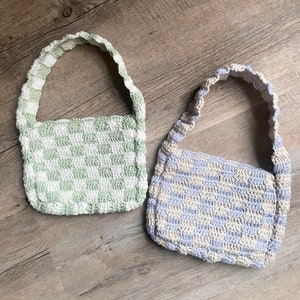 Könnte beinhalten: Zwei gehäkelte Handtaschen mit karierten Mustern. Eine ist grün und weiß, die andere ist hellblau und weiß.