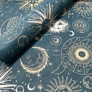 May include: Blue wrapping paper with a gold foil design of celestial bodies, including suns, moons, and stars. The design also includes zodiac symbols and constellations.