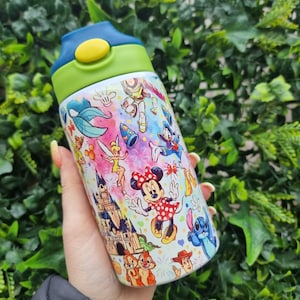 May include: A white water bottle with a green lid and a blue button. The bottle is covered in a colourful design featuring various Disney characters, including Mickey Mouse, Minnie Mouse, Donald Duck, Goofy, and Tinkerbell.