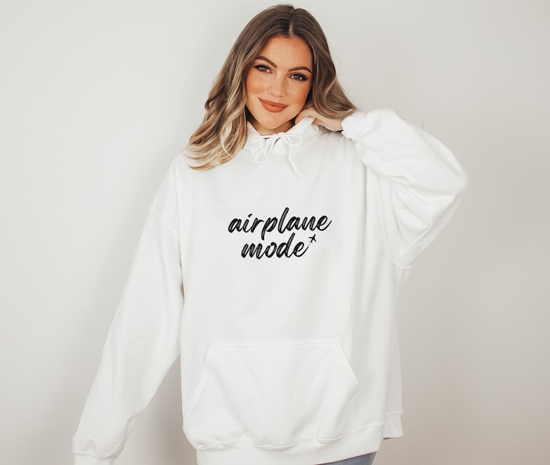 May include: White hoodie with a front pocket and drawstring hood. The phrase "airplane mode" is printed in black script across the chest, with a small airplane graphic. A casual, comfortable sweatshirt.