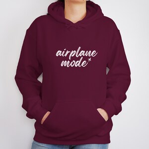 May include: A maroon hoodie with a front pocket and a drawstring hood. The white text "airplane mode" is printed across the chest, with a small airplane graphic. The hoodie is made of a soft material.