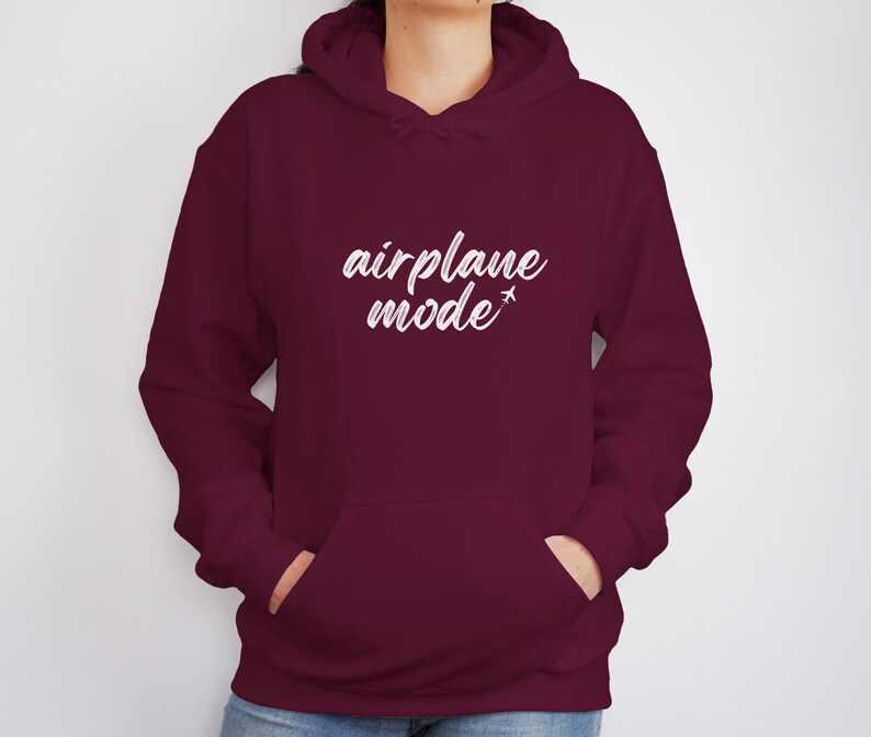 May include: A maroon hoodie with a front pocket and a drawstring hood. The white text "airplane mode" is printed across the chest, with a small airplane graphic. The hoodie is made of a soft material.