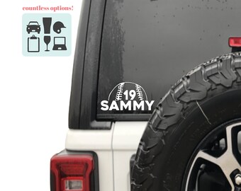 May include: White vinyl decal of a baseball with the number 19 and the name Sammy. The decal is on the back window of a white car.
