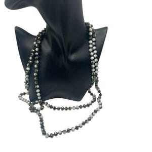 Puede incluir: Un collar de varias capas con cuentas blancas y negras. El collar está hecho de cuentas de vidrio facetadas y mide aproximadamente 76 cm de largo.