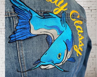 May include: A blue denim jacket with an embroidered catfish and the text "Stay Classy" in yellow thread.