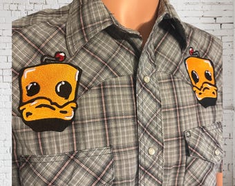 May include: A gray and pink plaid button-up shirt with two yellow embroidered cartoon duck patches on the front.