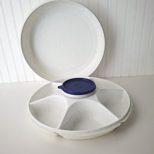 May include: A set of two speckled white plastic serving platters. One platter is divided into five sections, with a navy blue and white lid. The other is a solid, round platter. Ideal for serving snacks.