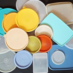May include: A collection of various plastic storage container lids in multiple shapes and sizes. The assortment includes round and rectangular lids in colors such as yellow, orange, blue, teal, green, beige, white, and translucent frosted plastic.