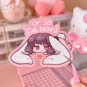 May include: A pink sticker featuring an anime-style character with dark purple hair and red eyes, peeking over a pink background. The sticker has the text "or so I've heard" and the artist's name.