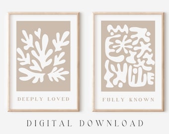 May include: Two beige framed prints with white abstract shapes. The left print says "Deeply Loved" and the right print says "Fully Known".