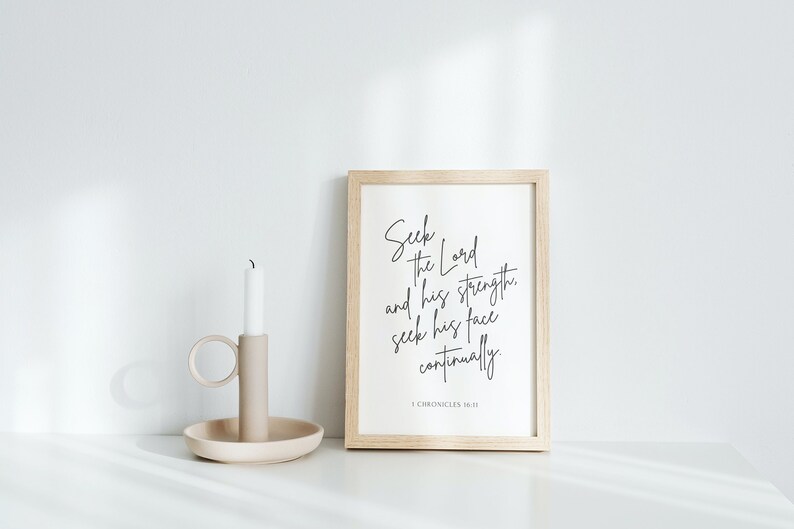 May include: A framed print with a white background and black text that reads "Seek the Lord and his strength, seek his face continually. 1 Chronicles 16:11". The frame is light wood and the print is sitting on a white surface.
