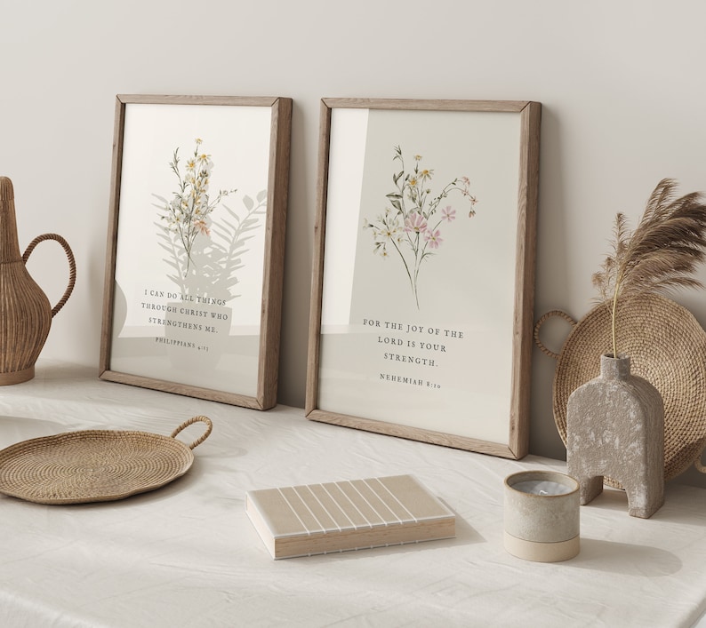 May include: Two framed art prints with floral designs and inspirational quotes. The prints have light wood frames and feature botanical illustrations in soft colors. One print reads "I CAN DO ALL THINGS THROUGH CHRIST WHO STRENGTHENS ME." The other reads "FOR THE JOY OF THE LORD IS YOUR STRENGTH."