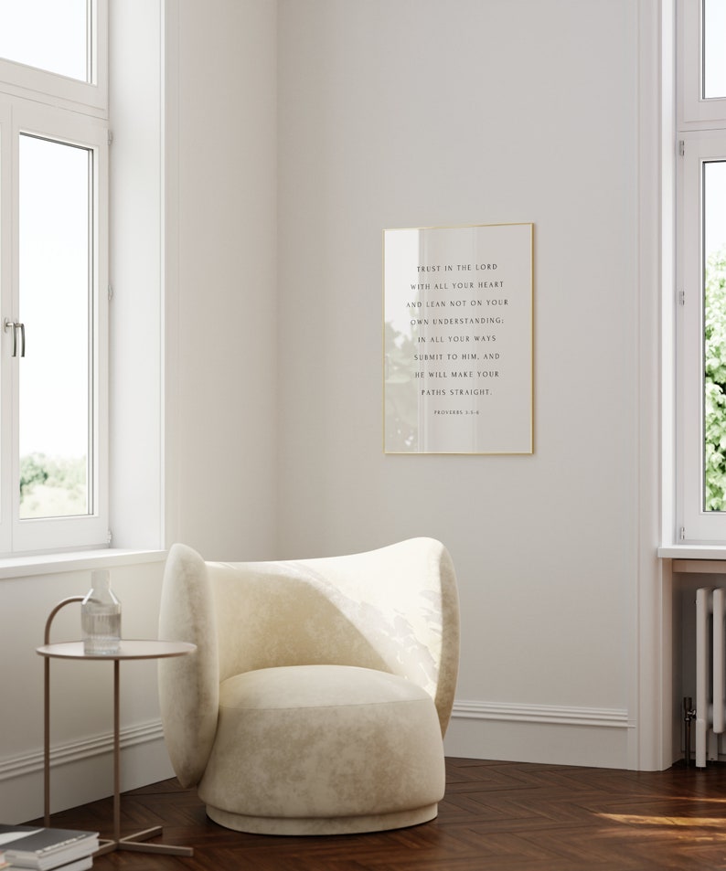 May include: A white armchair with a gold frame around a framed print with the text "Trust in the Lord with all your heart and lean not on your own understanding: In all your ways submit to him, and he will make your paths straight. Proverbs 3:5-6."