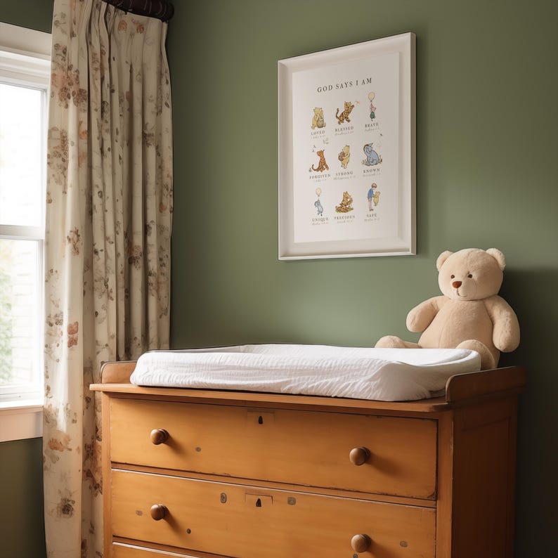 May include: A wooden dresser with three drawers, a white changing pad on top, and a stuffed teddy bear sitting on the floor. A framed Winnie the Pooh print with the text "God Says I Am" hangs on a green wall behind the dresser.