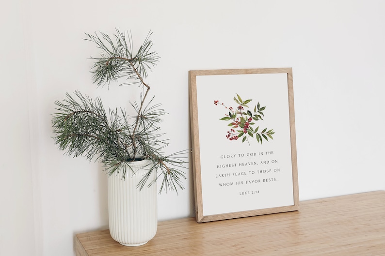 May include: A framed print with a white background and a floral illustration of red berries and green leaves. The print includes the text "Glory to God in the highest heaven, and on earth peace to those on whom his favor rests. Luke 2:14".