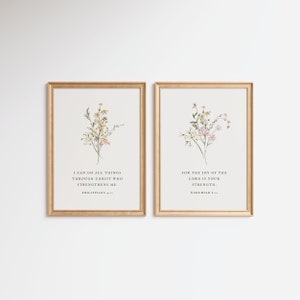 May include: Two framed art prints with gold frames. Each print features a floral watercolor design with text. One reads "I CAN DO ALL THINGS THROUGH CHRIST WHO STRENGTHENS ME. PHILIPPIANS 4:13." The other reads "FOR THE JOY OF THE LORD IS YOUR STRENGTH. NEHEMIAH 8:10."