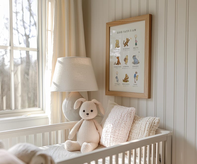 May include: A white crib with a white lamp and a stuffed animal in the shape of a bunny. The crib has a white blanket and a pink pillow. A framed print with the text "God Says I Am" is hanging on the wall.