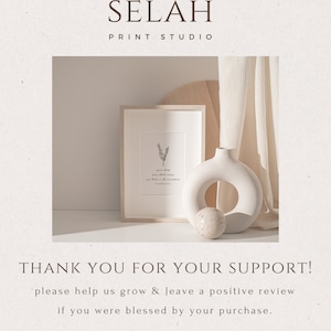 May include: A framed print with a minimalist design featuring a small sprig of rosemary and the text "spread loving kindness, your light will shine in all circumstances." The print is displayed on a wooden surface with a white ceramic vase and a speckled orb.