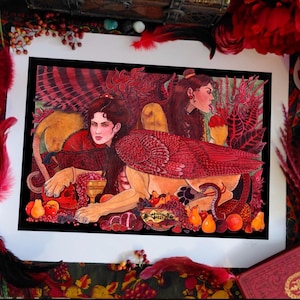 May include: A rectangular art print featuring two winged sphinx-like figures with human heads and feline bodies. The composition is dominated by deep red and orange tones, showcasing lush foliage, scattered fruits, a golden chalice, and a red skull.