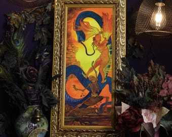May include: A rectangular framed artwork featuring a vibrant illustration of a skeleton and a figure interacting with a large blue serpent against a bright yellow background. The ornate gold frame has a detailed relief pattern along its edges.