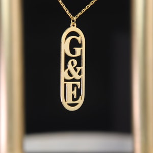 May include: Gold necklace with a pendant featuring the letters G & E in a rectangular frame.