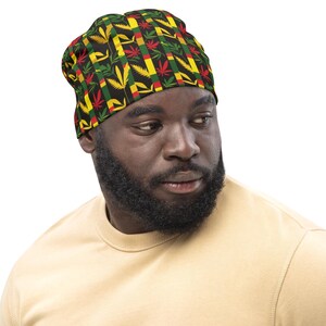 May include: A black beanie with a repeating pattern of green marijuana leaves, red and yellow stripes, and black lines.