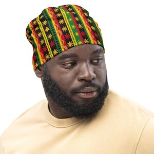 Pode incluir: Uma pessoa usando um gorro preto, vermelho, amarelo e verde com um design geométrico. O gorro tem um padrão de estrelas.