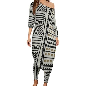May include: A white and black patterned dress with a geometric design. The dress has a one-shoulder neckline and a loose fit. The dress is paired with black pants.
