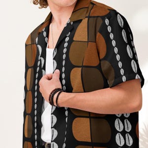 Puede incluir: Camisa negra de manga corta con un estampado geométrico en tonos marrón y blanco. La camisa tiene un cuello clásico. El diseño presenta formas abstractas y líneas verticales. Tejido ligero.