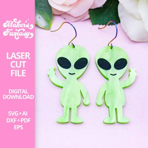 Könnte beinhalten: Ein Paar grüne Alien-Ohrringe mit einer Peace-Handgeste. Die Ohrringe sind aus lasergeschnittenem Holz und haben einen hellgrünen Aquarelleffekt. Die Ohrringe hängen an silbernen Haken.