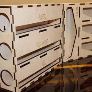 May include: A wooden organizer with three compartments labeled "FOIL", "PARCHMENT", and "PLASTIC". The organizer has a separate section with slots for various items, including "LANOLIN", "WAX", and "SOAP".