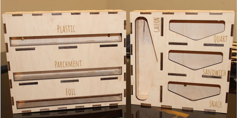 May include: A wooden storage box with two sections. The left section has three slots labeled "Plastic", "Parchment", and "Foil". The right section has four slots labeled "Gallon", "Quart", "Sandwich", and "Snack".