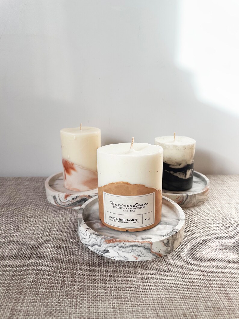 Pu&ograve; includere: Tre candele profumate bianche e marroni su sottobicchieri di marmo. La candela centrale ha un'etichetta che recita "Maison & Luxe Candela profumata di lusso 2,5 oz / 90 g Oud & Bergamotto Uva, Geranio, Agrumi N. 1"