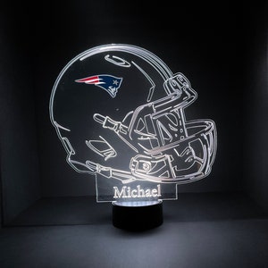 May include: A white, illuminated, 3D printed night light shaped like a football helmet with the New England Patriots logo on the side. The name "Michael" is printed below the helmet.