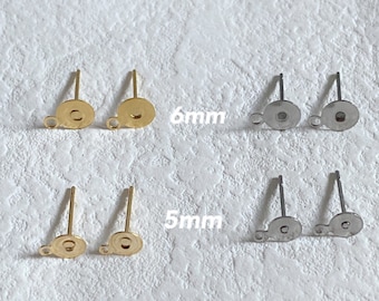 May include: A collection of earring posts in gold and silver tones. The posts are shown in pairs, with two sizes: 5mm and 6mm. The image includes the measurements in millimeters. The earring posts have a flat, round base with a loop for attaching earrings.
