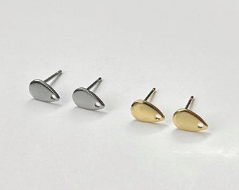 May include: A pair of silver and gold teardrop shaped earrings with a small hole in the center of each teardrop.