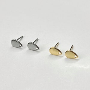 May include: A pair of silver and gold teardrop shaped earrings with a small hole in the centre of each teardrop.