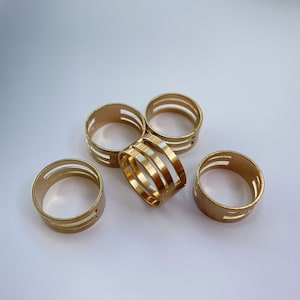 May include: Five gold-coloured metal rings with a decorative cut-out design. The rings are stacked on top of each other.