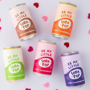 May include: Five soda pop cans with the text "Be My Little Soda Pop" in various colors, including brown, orange, green, red, and purple. The cans are decorated with hearts and the phrase "Happy Valentine's Day".