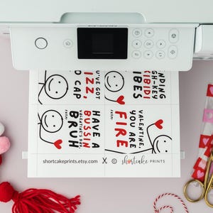 Op de afbeelding: Printbare Valentijnsdagkaarten met grappige spreuken en stick figure illustraties. De kaarten bevatten zinnen als "You are Fire", "Have a Bussin' Valentine's Day, Bruh" en "I've Got Izz, D Cap".