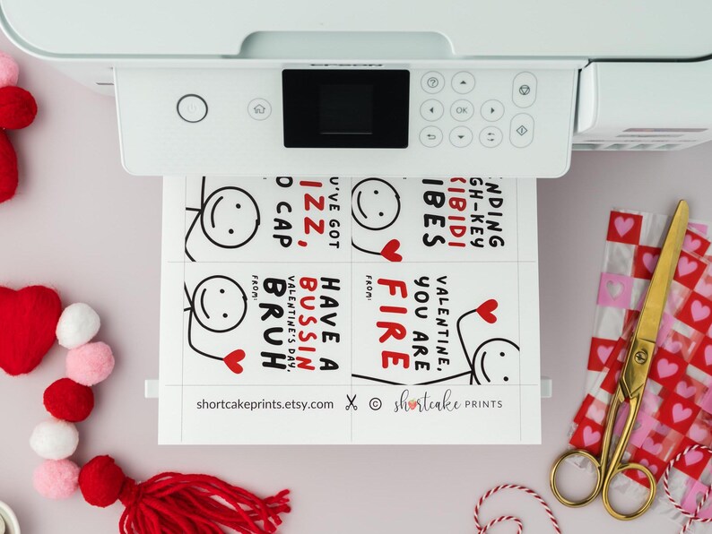 Op de afbeelding: Printbare Valentijnsdagkaarten met grappige spreuken en stick figure illustraties. De kaarten bevatten zinnen als "You are Fire", "Have a Bussin' Valentine's Day, Bruh" en "I've Got Izz, D Cap".