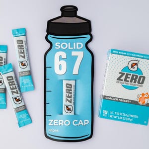 May include: A promotional image featuring Gatorade Zero products. The image includes a large, blue bottle-shaped display with the text "SOLID 67" and "ZERO CAP." Several Glacier Freeze packets and a box of Zero sugar thirst quencher powder are also visible.