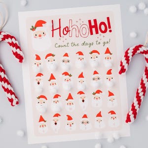 Peut inclure: Image sur le thème de Noël avec deux décorations en forme de canne en bonbon rouge et blanc et un calendrier de compte à rebours. Le calendrier affiche des visages de Père Noël et le texte "HoHoHo! Count the days to go!"