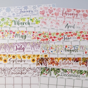 May include: A stack of 2026 calendars, each featuring a different month with floral and seasonal designs. January has snowflakes, February has hearts, March has shamrocks, and April has flowers. The calendars are printed on white paper.