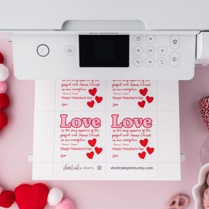 K&ouml;nnte beinhalten: Druckbare Valentinstagskarten in einem rosa und roten Farbschema. Die Karten zeigen den Text "Liebe ist die Essenz des Evangeliums und Jesus Christus ist unser Vorbild." mit drei roten Herzen. Die Karten sind auf wei&szlig;em Papier gedruckt.