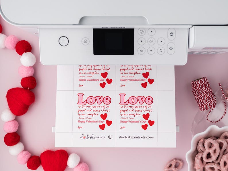 K&ouml;nnte beinhalten: Druckbare Valentinstagskarten in einem rosa und roten Farbschema. Die Karten zeigen den Text "Liebe ist die Essenz des Evangeliums und Jesus Christus ist unser Vorbild." mit drei roten Herzen. Die Karten sind auf wei&szlig;em Papier gedruckt.