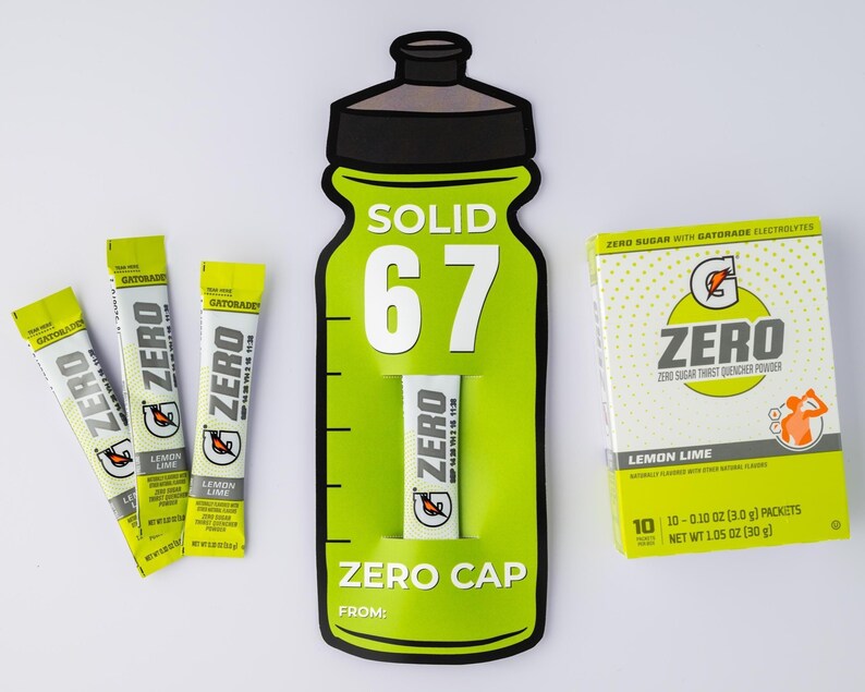 May include: A still-life image featuring Gatorade Zero products. The composition includes a large green bottle-shaped display with the text "SOLID 67" and "ZERO CAP", along with individual packets and a box of Lemon Lime flavoured powder. The packets and box feature the "ZERO" logo.