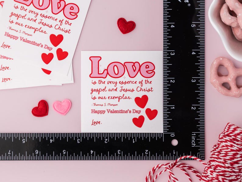 K&ouml;nnte beinhalten: Eine wei&szlig;e Karte mit rosa und roten Herzen und dem Text "Liebe ist die wahre Essenz des Evangeliums und Jesu Christi, er ist unser Vorbild. -Thomas S. Monson Froher Valentinstag Liebe."
