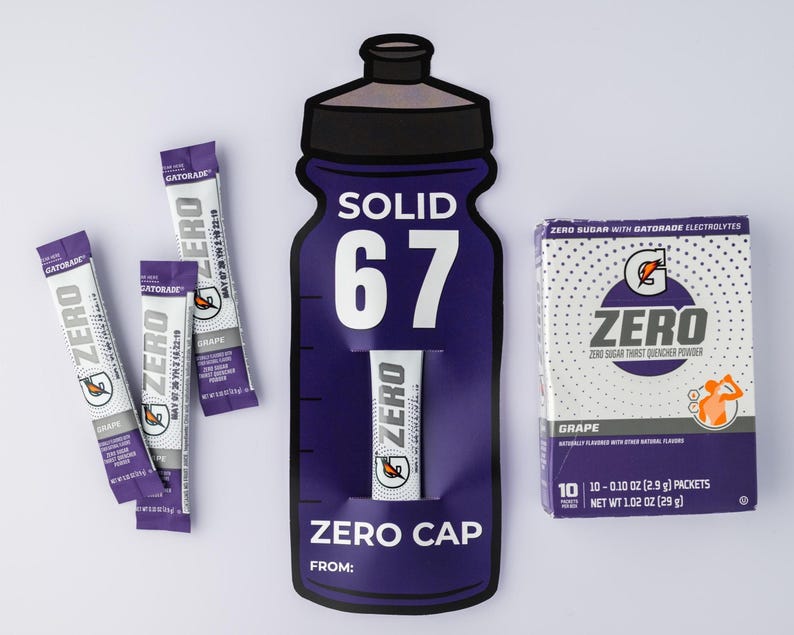 May include: Image of Gatorade Zero products. The composition includes individual packets, a box of grape-flavored powder, and a large purple bottle-shaped display. The box contains 10 packets, each 2.9 grams.